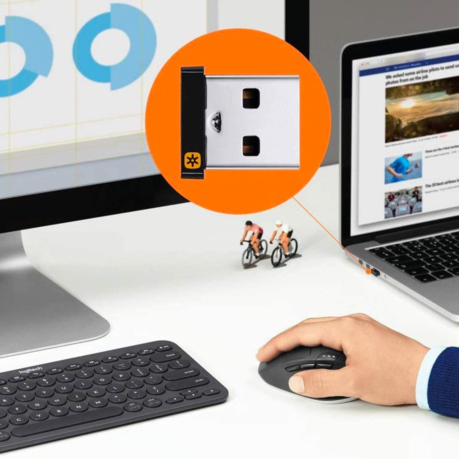 Eine Person benutzt eine Maus neben einer Tastatur und einem Computerbildschirm. Ein USB-Gerät ist im Fokus.