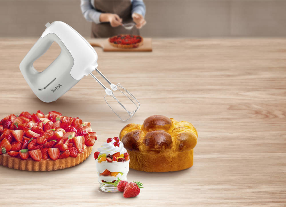 Kézi mixer különböző desszertekkel, beleértve a tortát és a brióst.