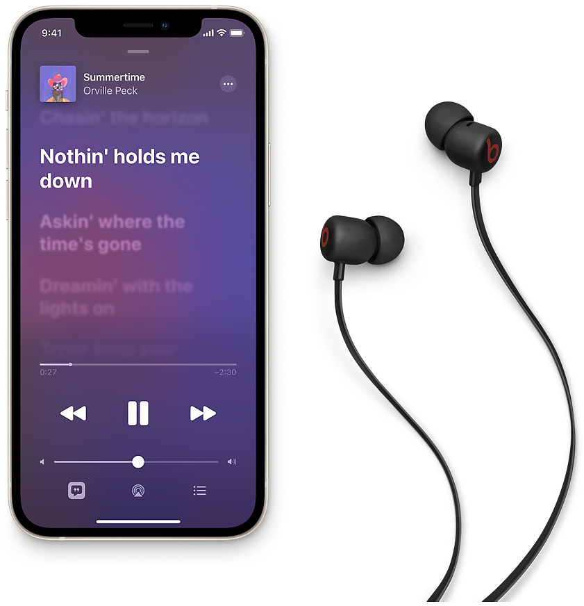 Schwarze Beats Ohrhörer neben einem iPhone mit Musik-App.