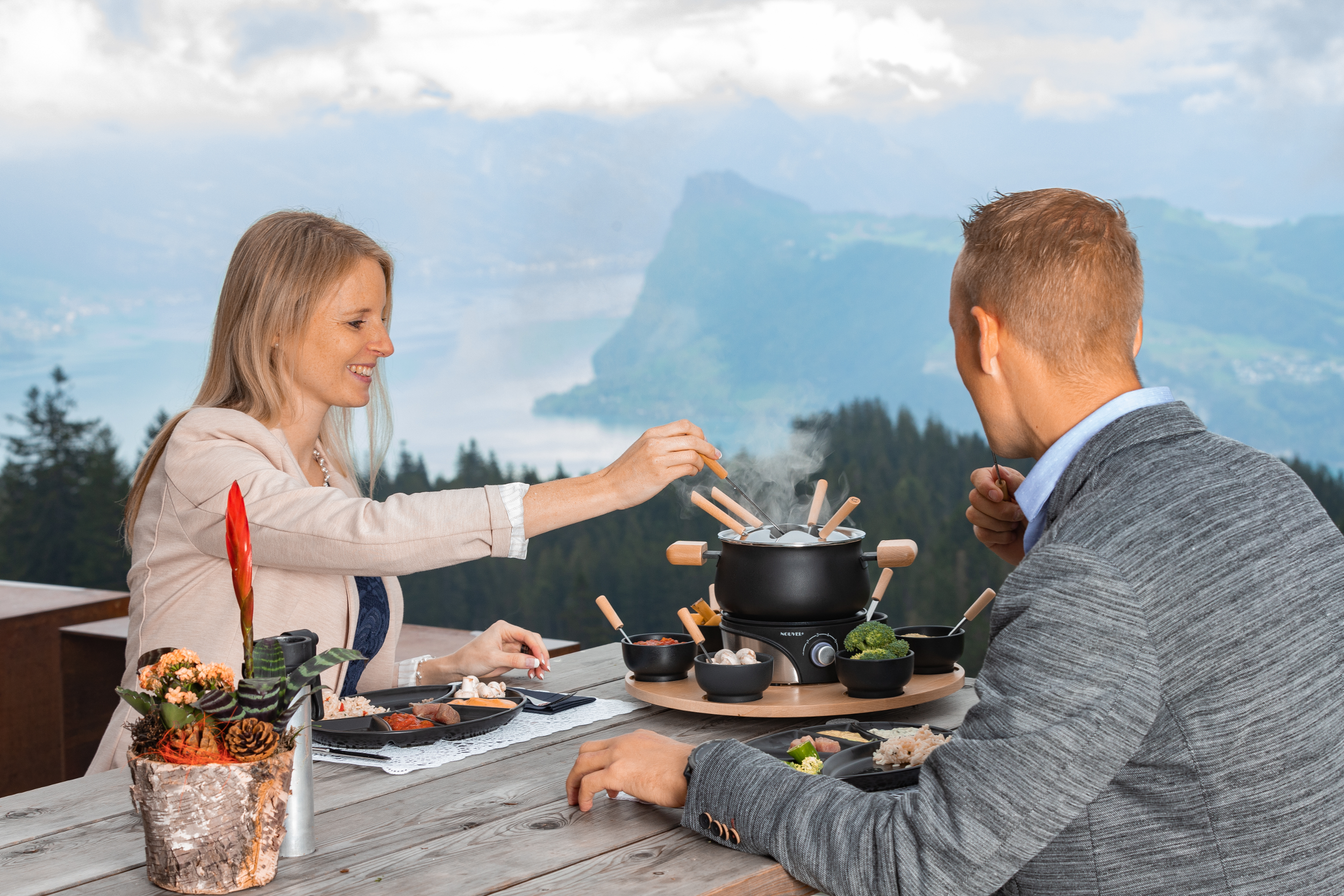 Una coppia che si gode la fonduta all'aperto, con le montagne sullo sfondo.