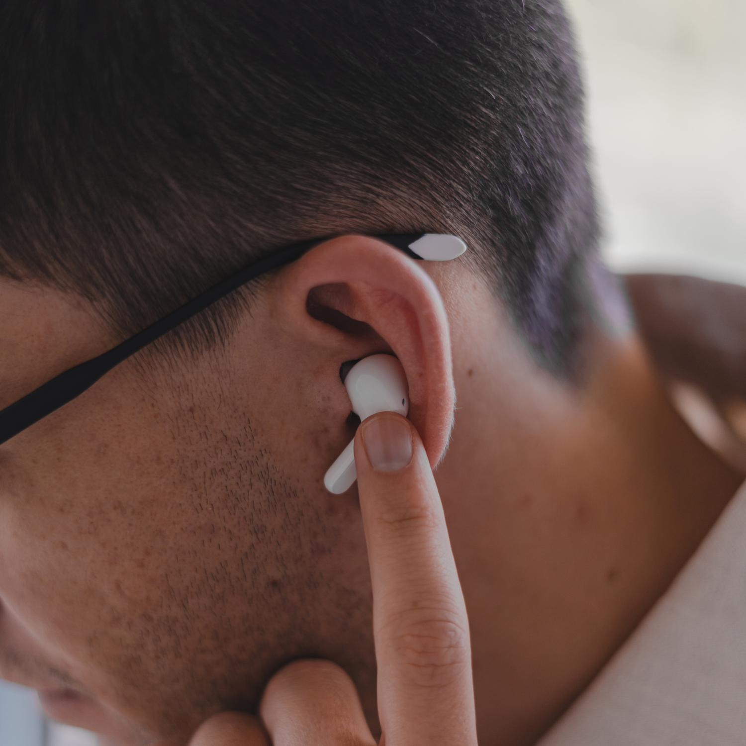 Primer plano de un hombre insertando un auricular blanco en su oído.