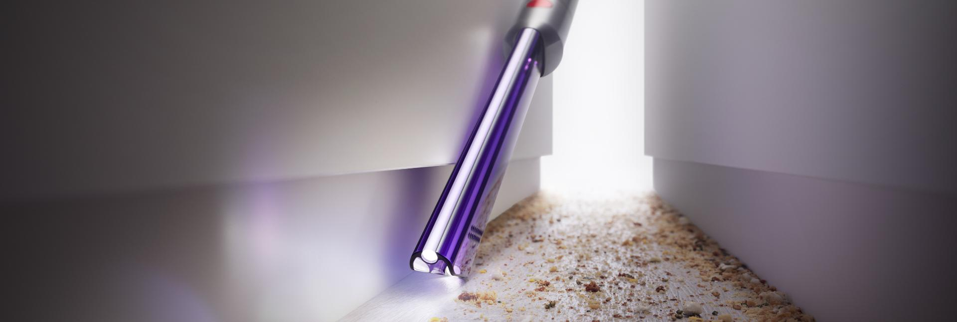 Nahaufnahme eines Staubsaugerkopfes, der eine Ecke reinigt.