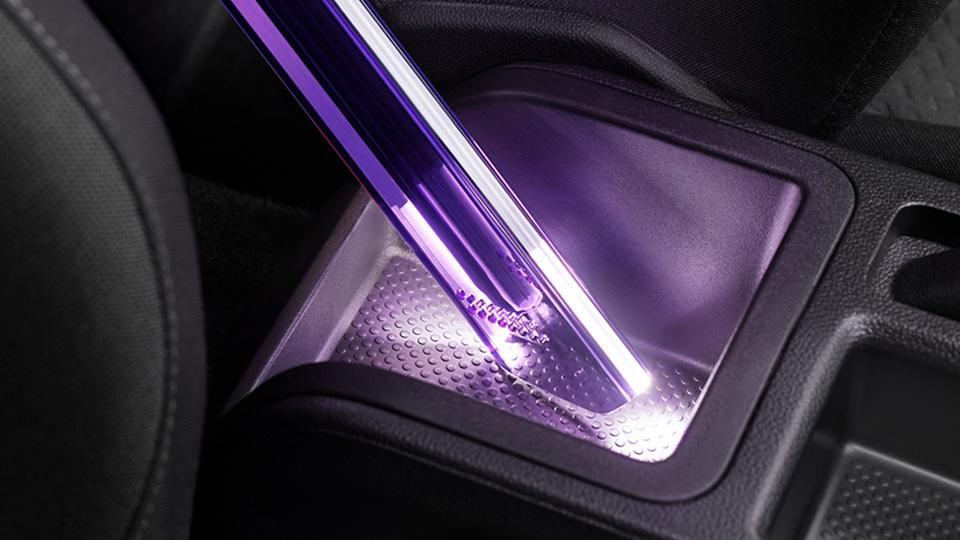 Autokonsole mit einem violetten Licht, das in ein kleines Fach scheint. Innenraum eines Autos.
