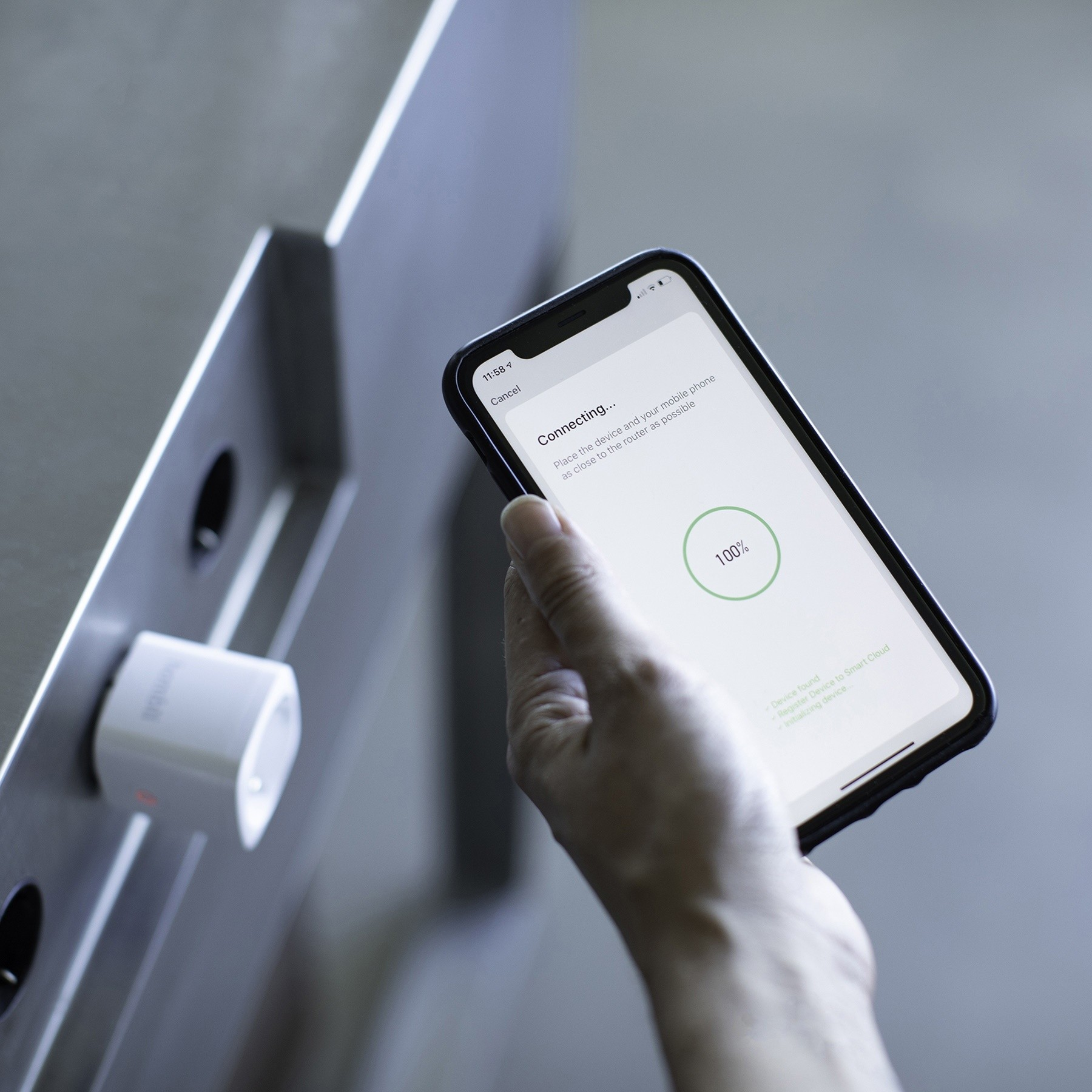 Une personne tenant un téléphone se connectant à une prise intelligente.