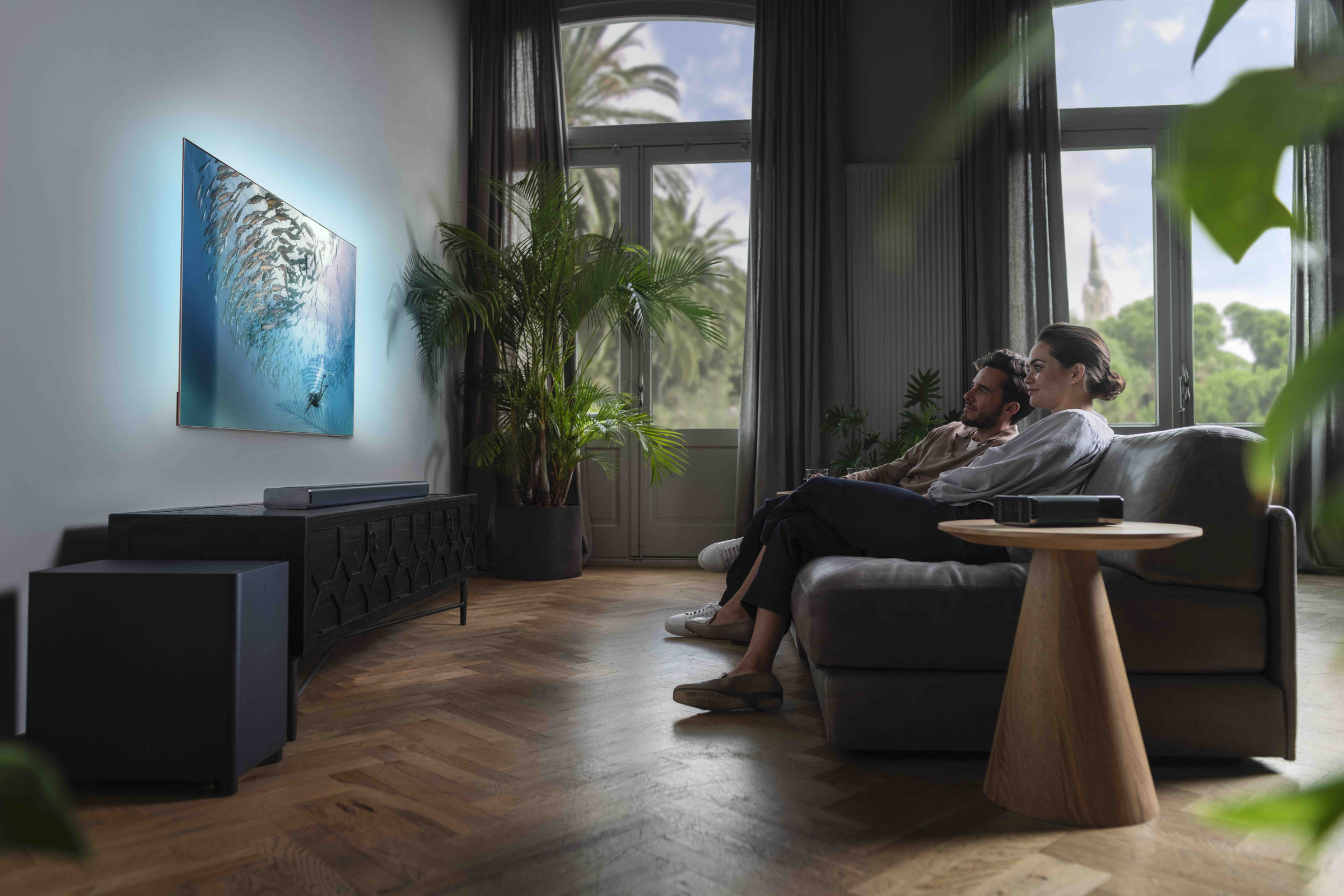 Paar auf Couch schaut TV mit blauem Licht im Wohnzimmer.