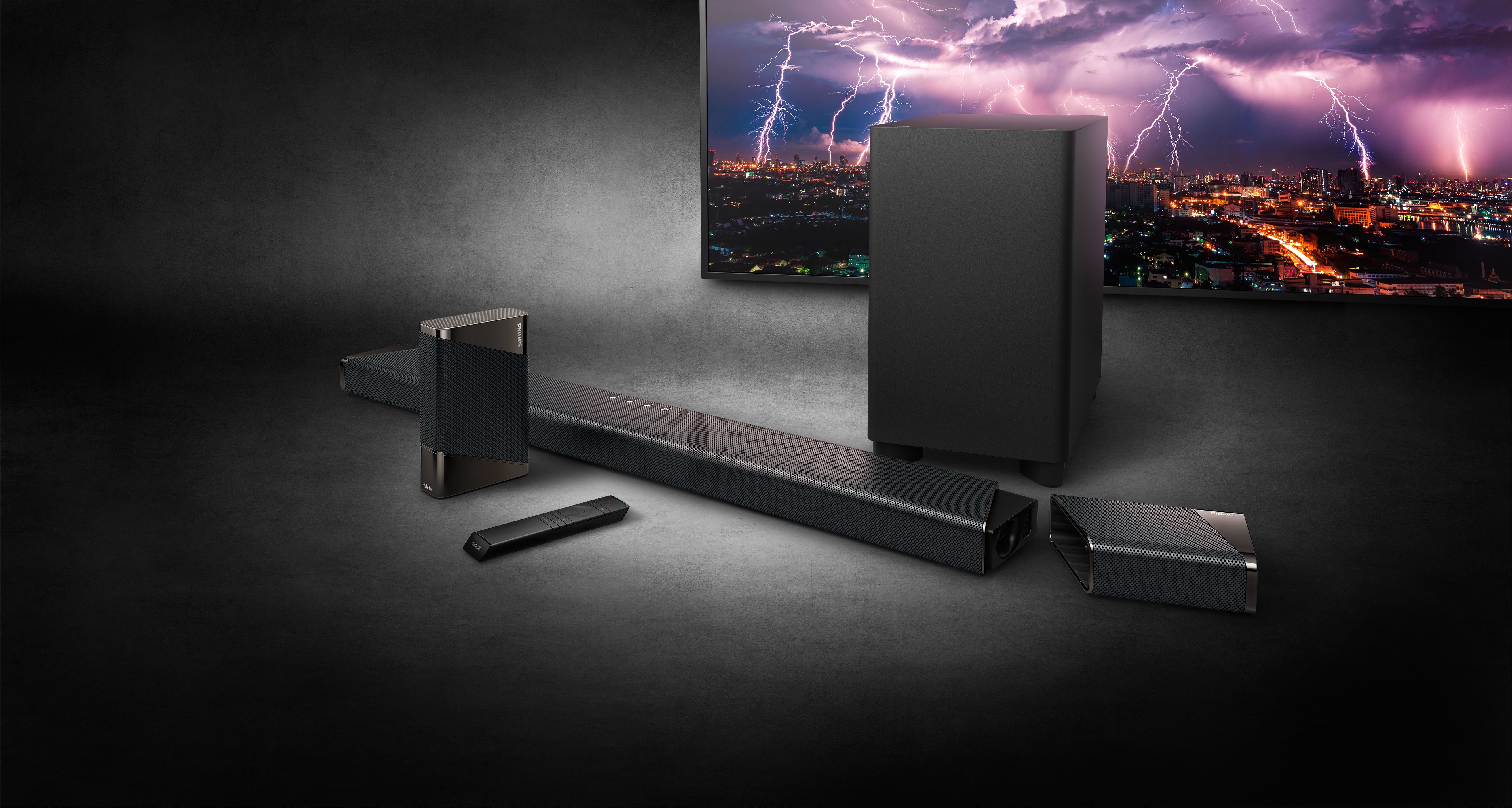 Schwarzes Soundsystem mit einem Fernsehbildschirm, der ein Gewitter zeigt. Enthält eine Soundbar, einen Subwoofer und Lautsprecher.