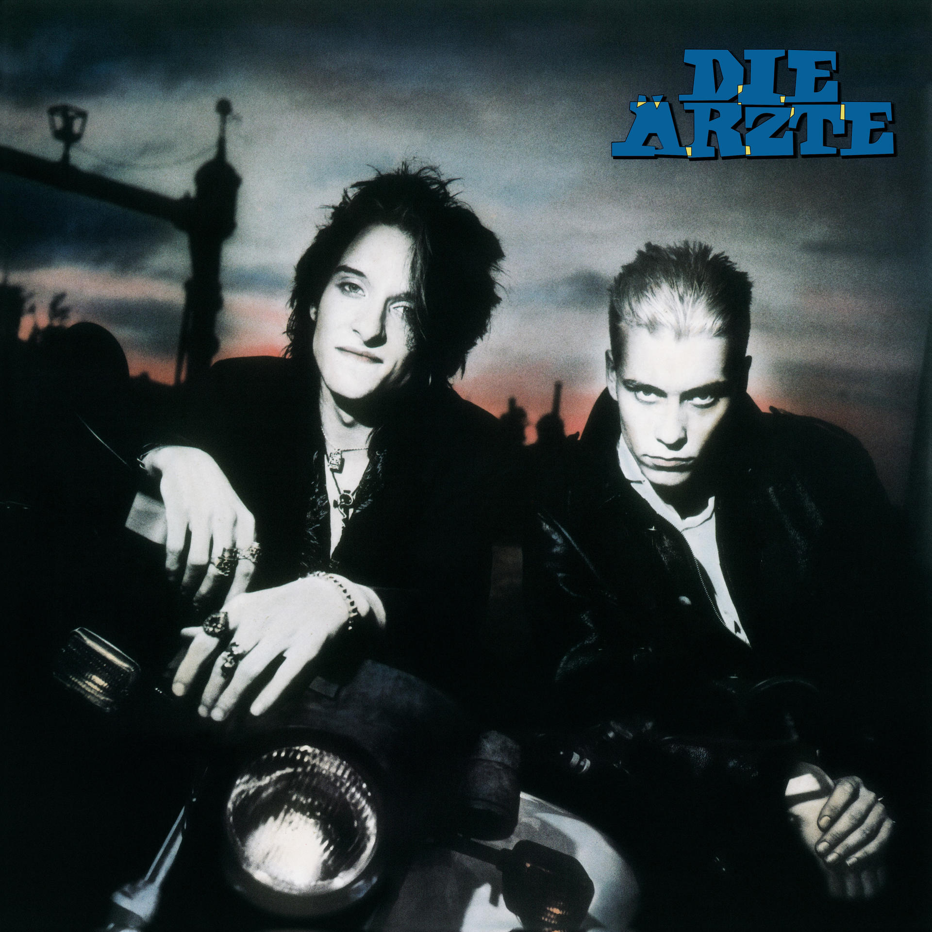 Albumcover mit zwei Männern. Titel: Die Ärzte. Ein Mann sitzt auf einem Motorrad. Der Hintergrund ist dunkel.