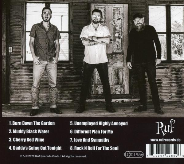 Drei Männer stehen neben einem Holzgebäude, Albumcover mit einer Titelliste.
