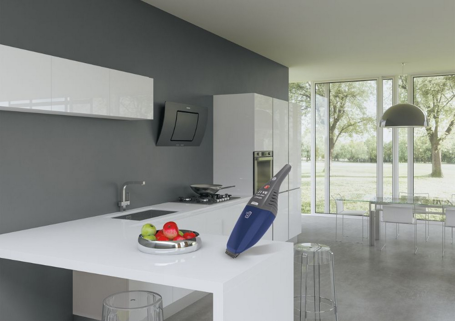 Aspiradora de mano azul y gris en una encimera de cocina, cerca de fruta y un fregadero.