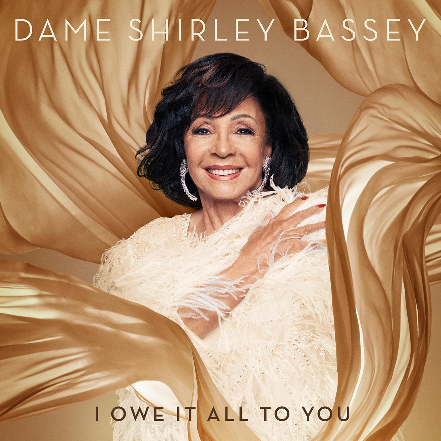 Dame Shirley Bassey, lächelnd, mit goldenem Stoff im Glamour-Shot.