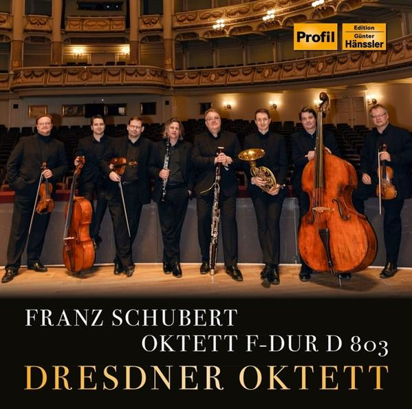 Albumhoes, een groep mannen met instrumenten, in een zaal, titel en artiestennaam.