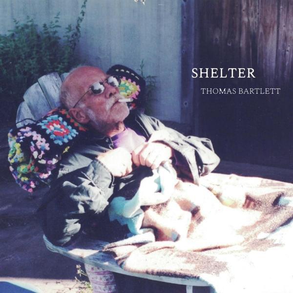 Albumcover eines älteren Mannes beim Rauchen, draußen sitzend, mit dem Text 'SHELTER'.