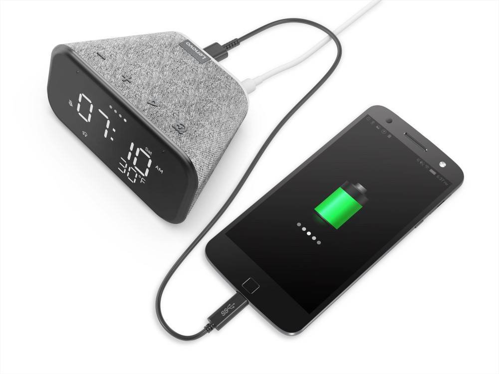 Un altavoz gris está cargando un teléfono inteligente negro con un símbolo de batería verde.