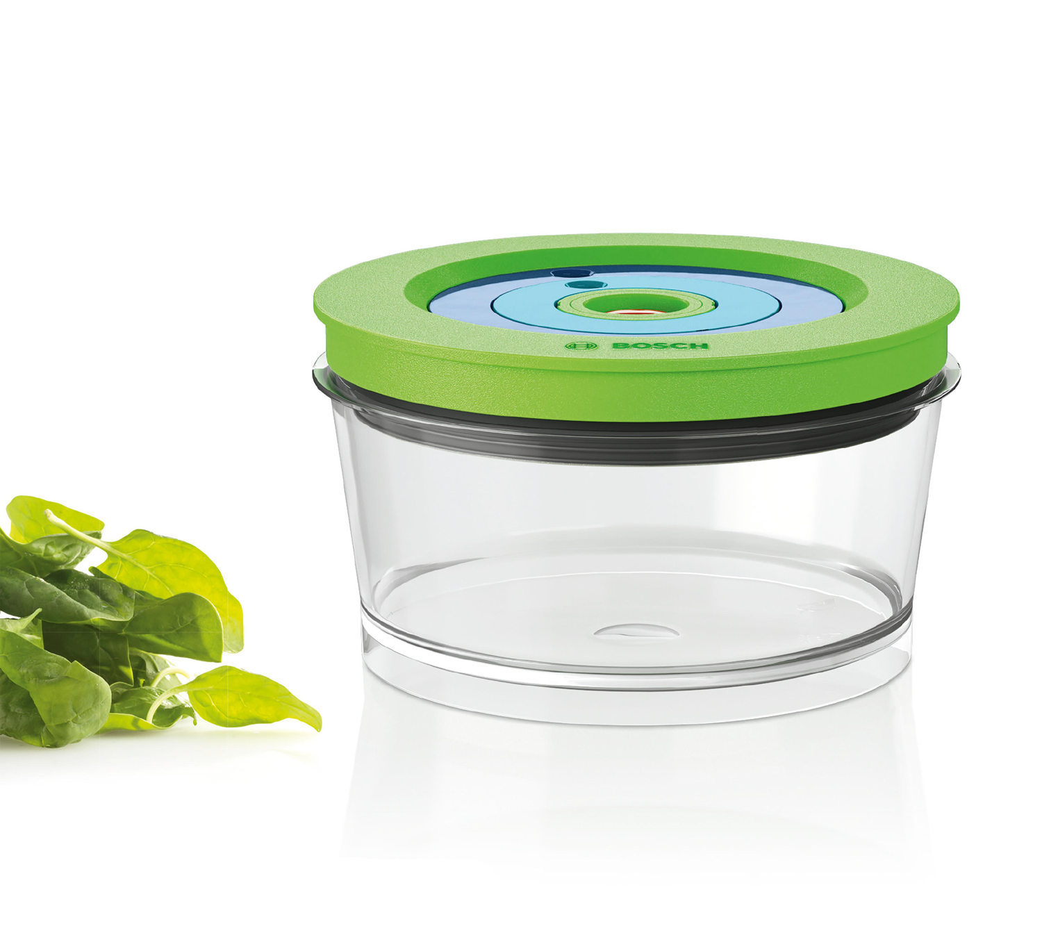 Een doorzichtige voedselcontainer met een groen deksel, naast een hoop groene spinaziebladeren, op een witte achtergrond.