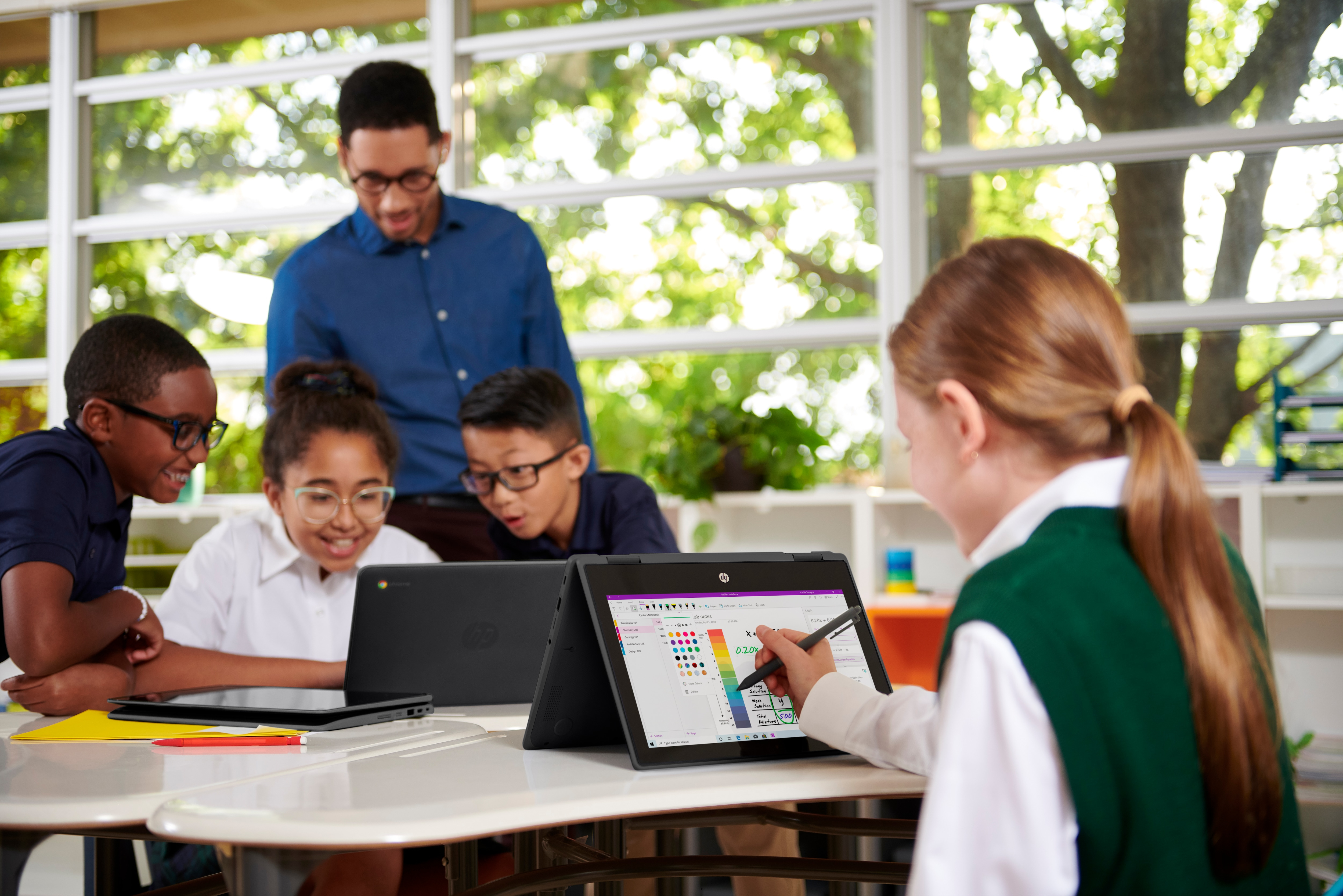 Escena de aula con estudiantes usando computadoras portátiles HP y un profesor.