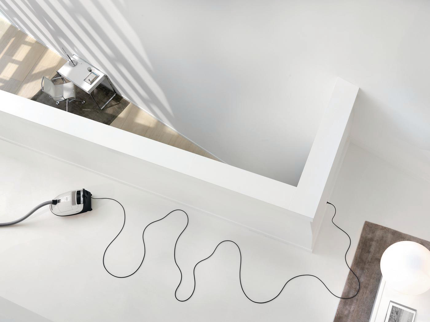 Draufsicht auf einen weißen Raum mit Staubsauger und Kabel.