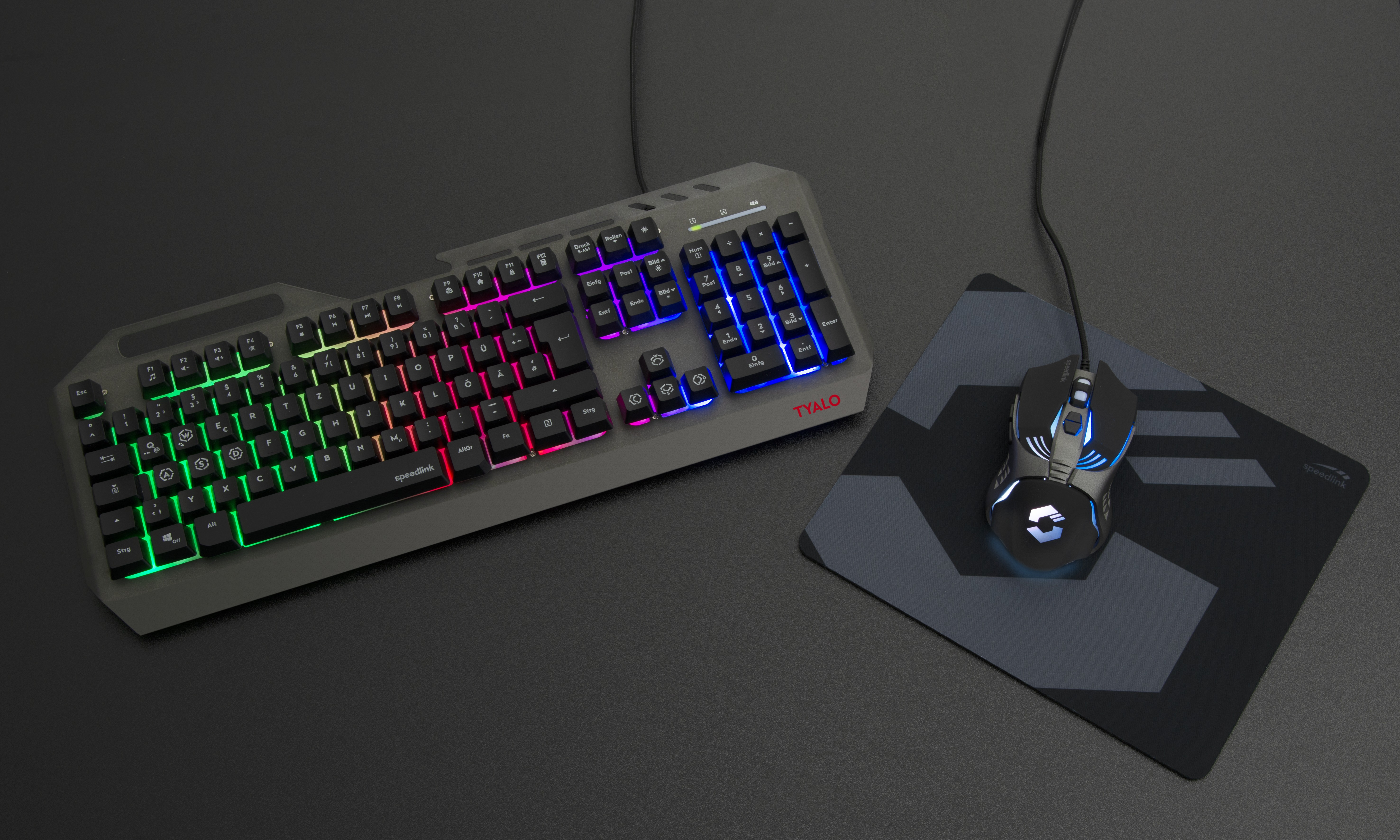 Gaming-Tastatur und -Maus auf schwarzer Oberfläche. Die Tastatur hat bunte Lichter. Die Maus hat blaue Lichter.