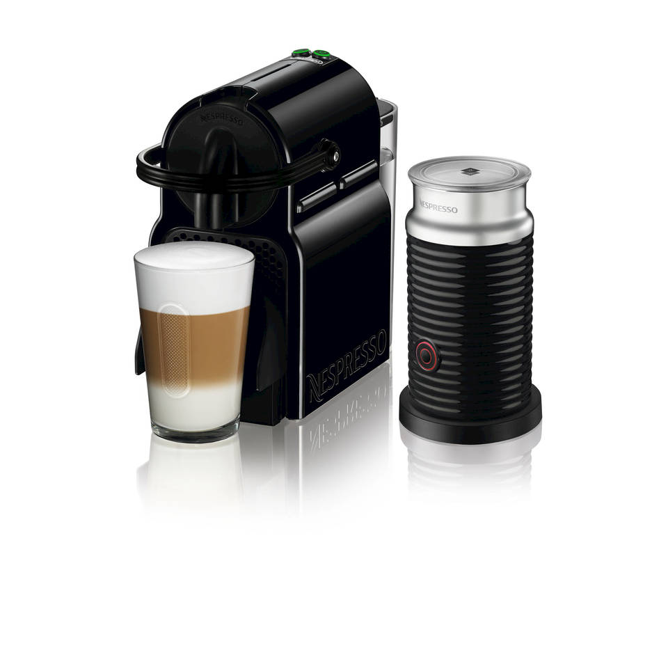 Eine schwarze Nespresso-Maschine mit einem Latte-Glas und Milchaufschäumer auf weißer Oberfläche.