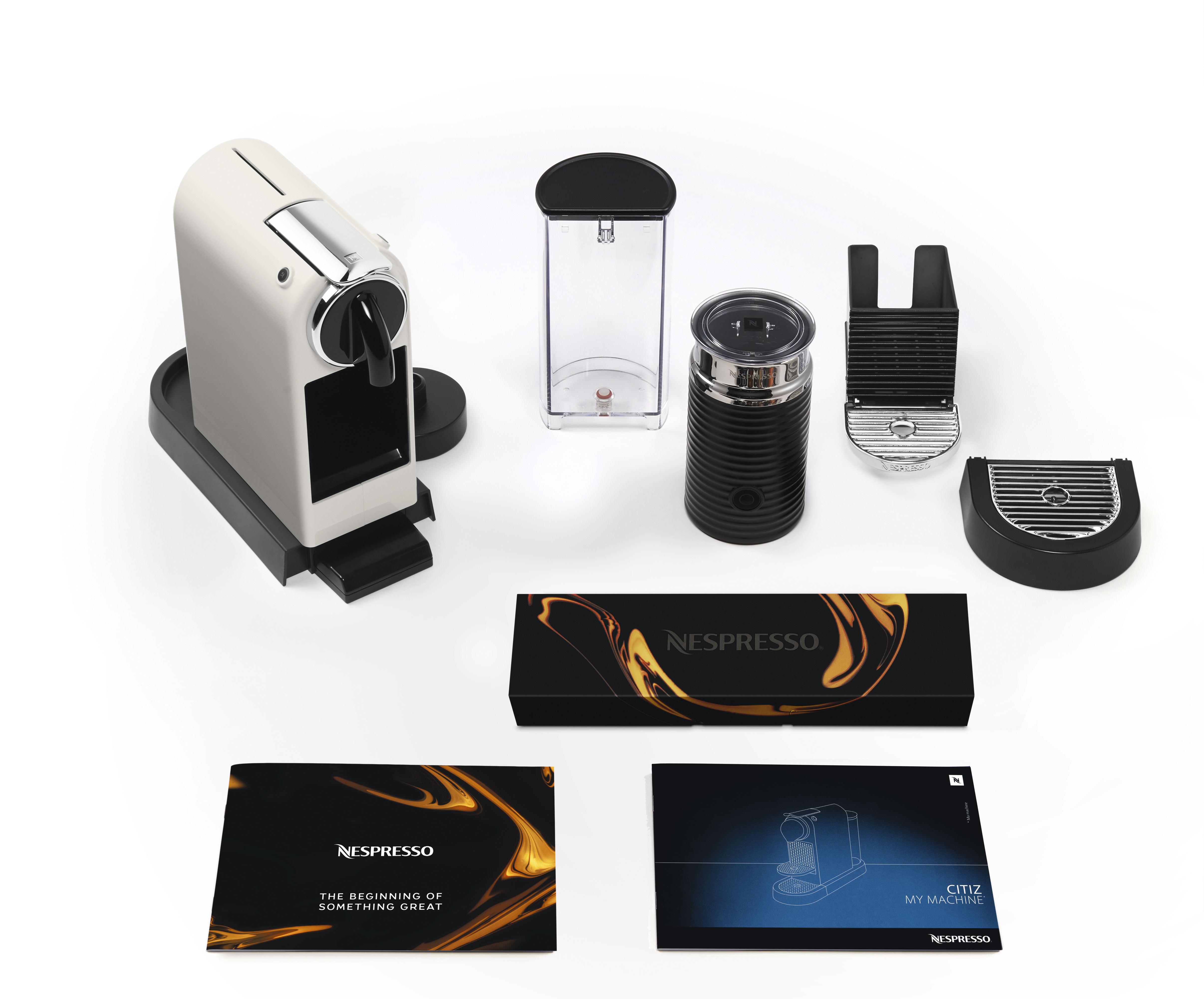 Kaffeemaschine und Zubehör: weiße Maschine, schwarzer Milchaufschäumer, Wassertank und Anleitung.