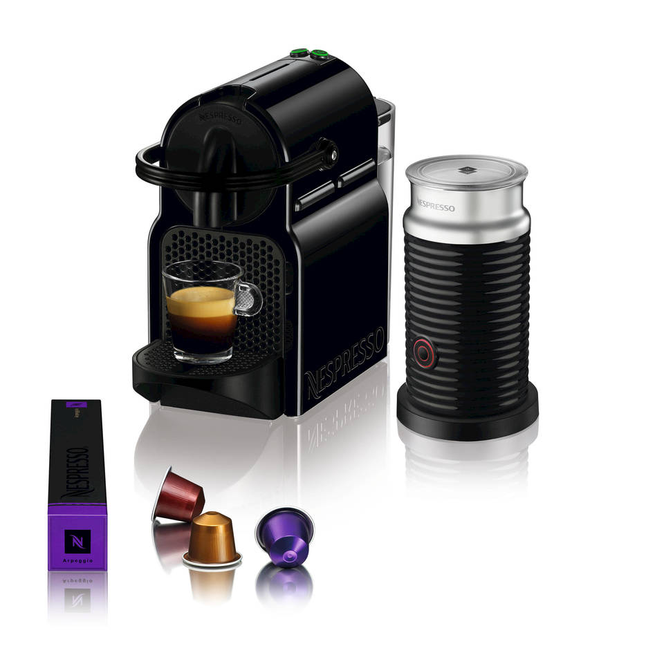 Schwarze Nespresso-Maschine mit Milchaufschäumer, Kapseln und einer Tasse Kaffee.