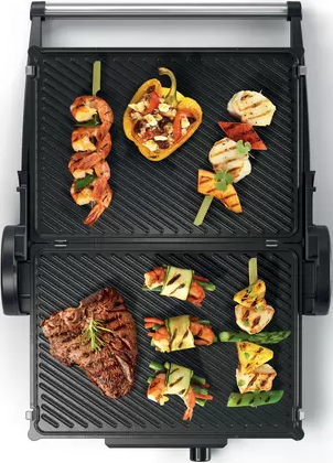 Gril avec aliments grillés: steak, brochettes de crevettes, poivrons et légumes.