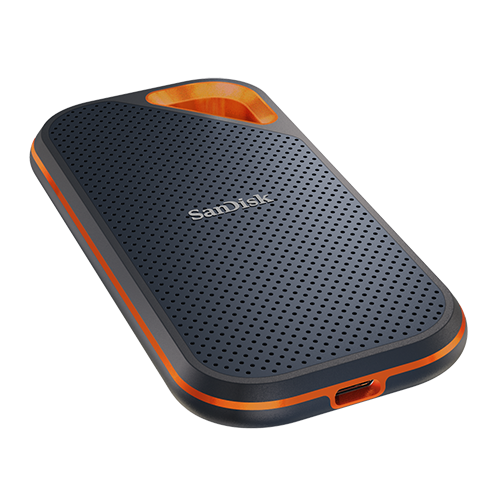 Zwarte en grijze Sandisk externe harde schijf met oranje accenten. Op een donkere achtergrond.