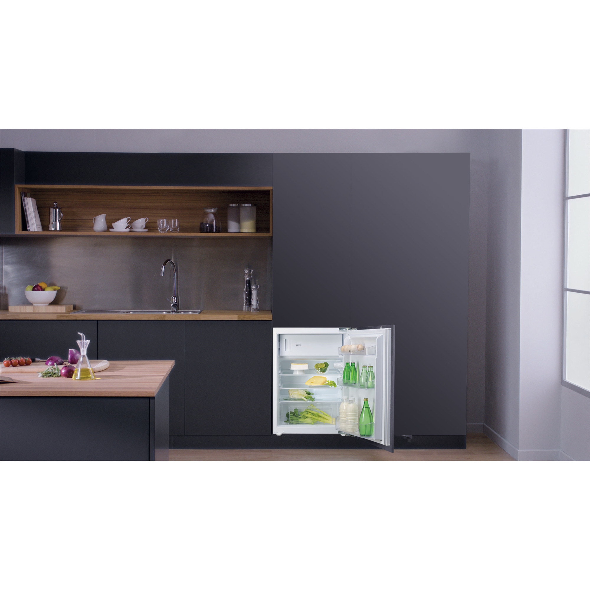 Eine Küche mit offenem Kühlschrank, der Lebensmittel zeigt. Eine Person kocht auf der Insel.