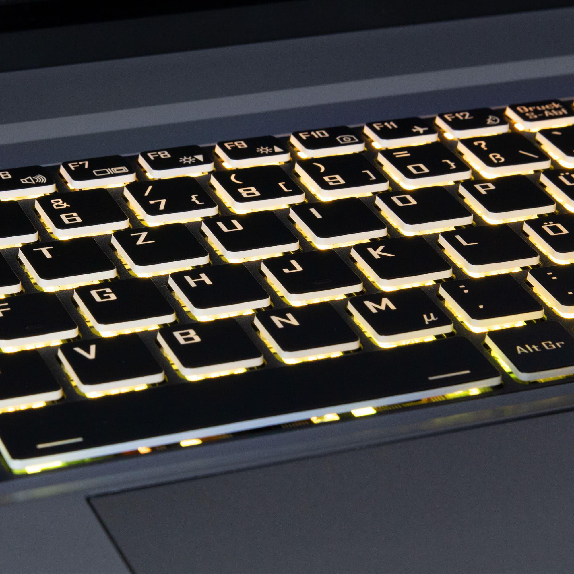 Nahaufnahme einer Laptop-Tastatur mit beleuchteten Tasten und schwarzem Layout auf grauem Gehäuse.