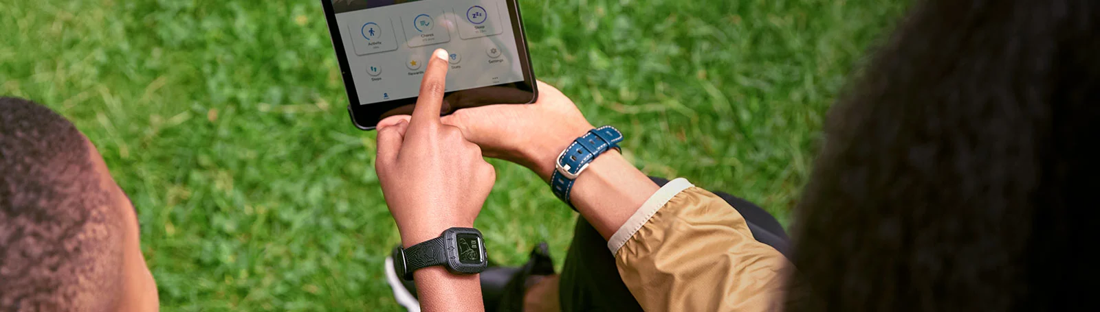 Hände, die im Freien ein Tablet benutzen, mit einer Uhr am Handgelenk.
