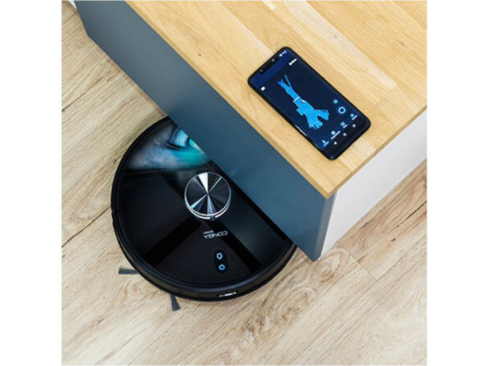 Aspiradora robot negra en suelo de madera, cerca de un smartphone mostrando una app.