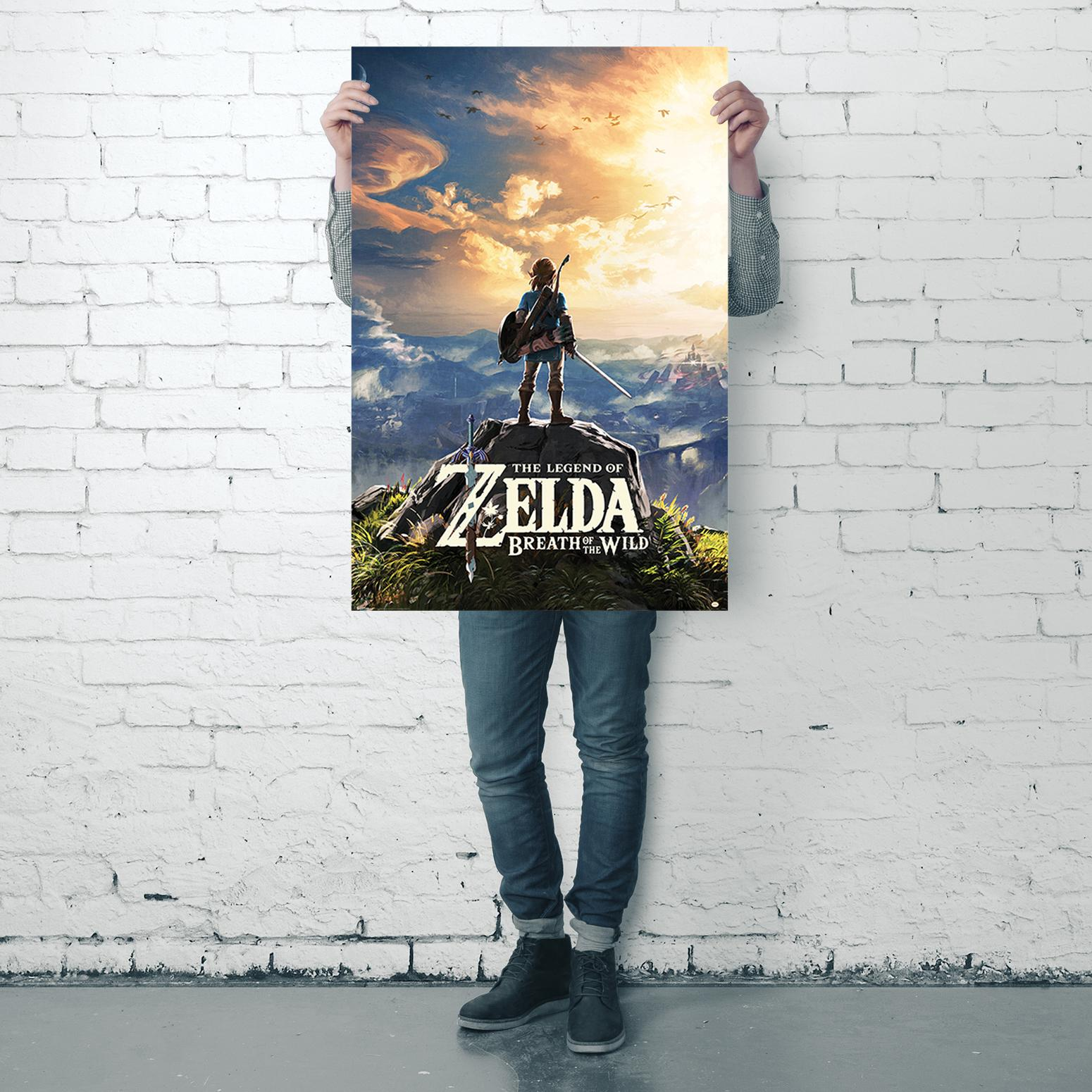 Person hält ein Poster von 'The Legend of Zelda: Breath of the Wild'. Poster zeigt eine malerische Landschaft.