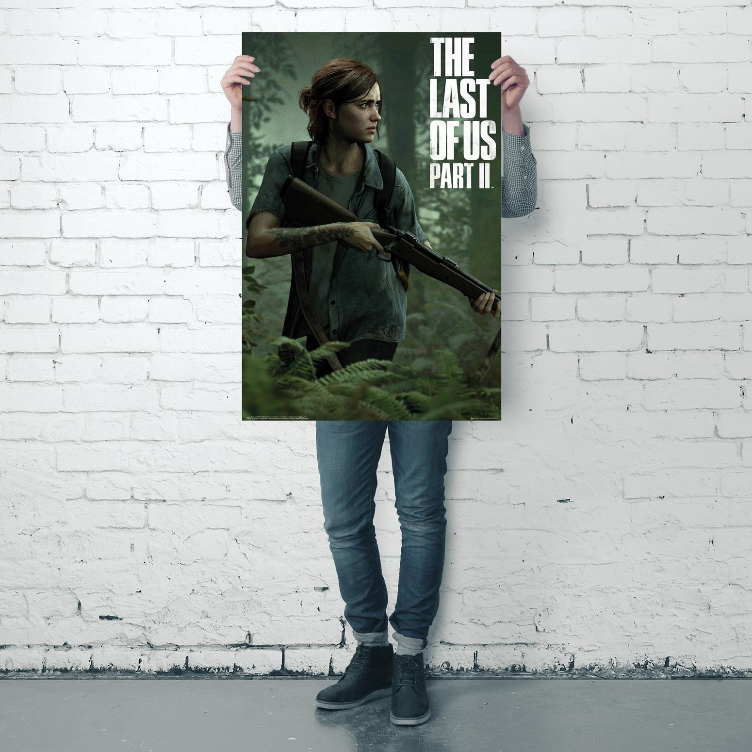 Eine Person hält ein Poster von "The Last of Us Part II". Die Person trägt Jeans und ein kariertes Hemd.
