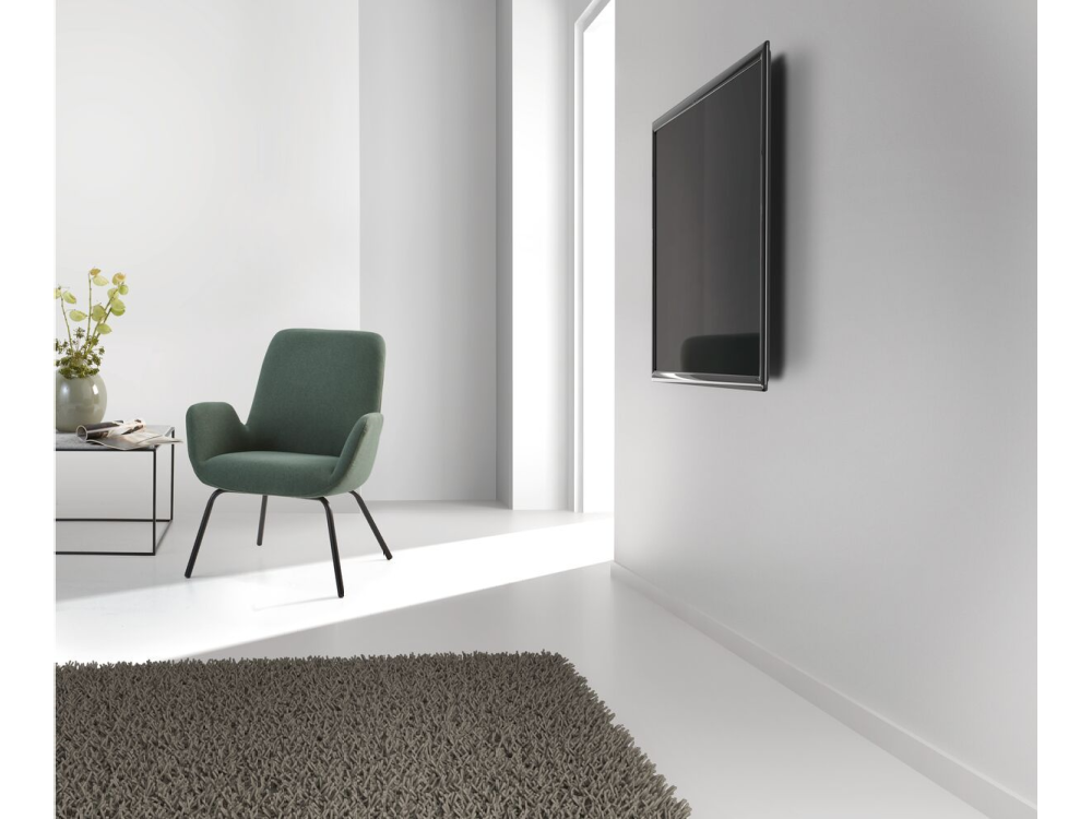 Una habitación con una silla verde, una mesa negra con un jarrón y una alfombra gris oscura.