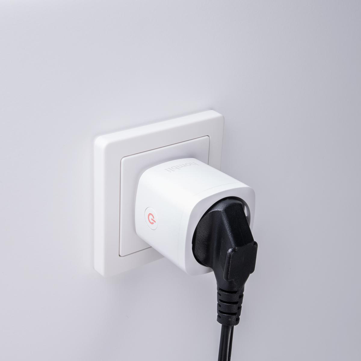 Weißer Smart-Stecker in einer Steckdose, schwarzer Stecker angeschlossen. Weißer Wandhintergrund.