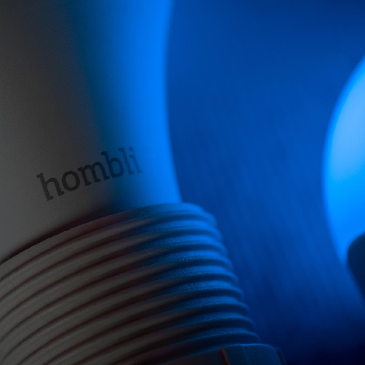 Nahaufnahme eines weißen Objekts mit dem Wort 'homblí' und blauem Licht im Hintergrund.