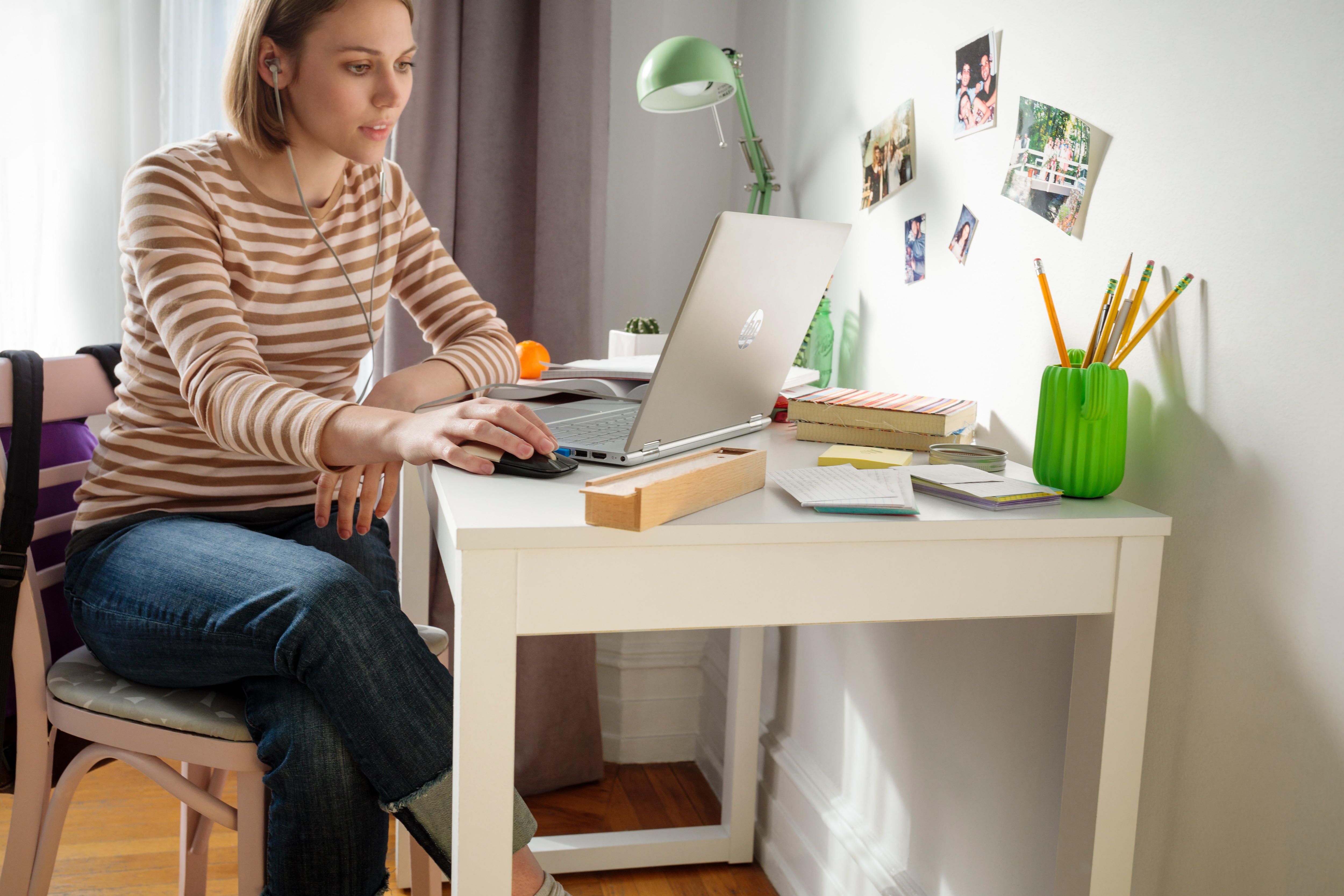 Eine junge Frau benutzt einen Laptop an einem weißen Schreibtisch.