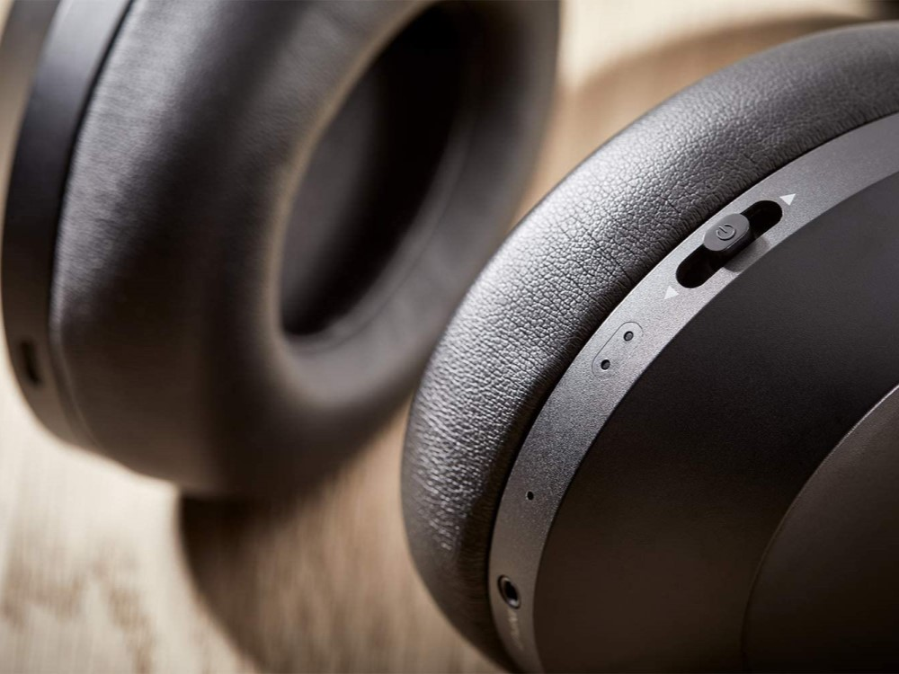 Dos auriculares negros, primer plano. El derecho muestra botones y un dial.