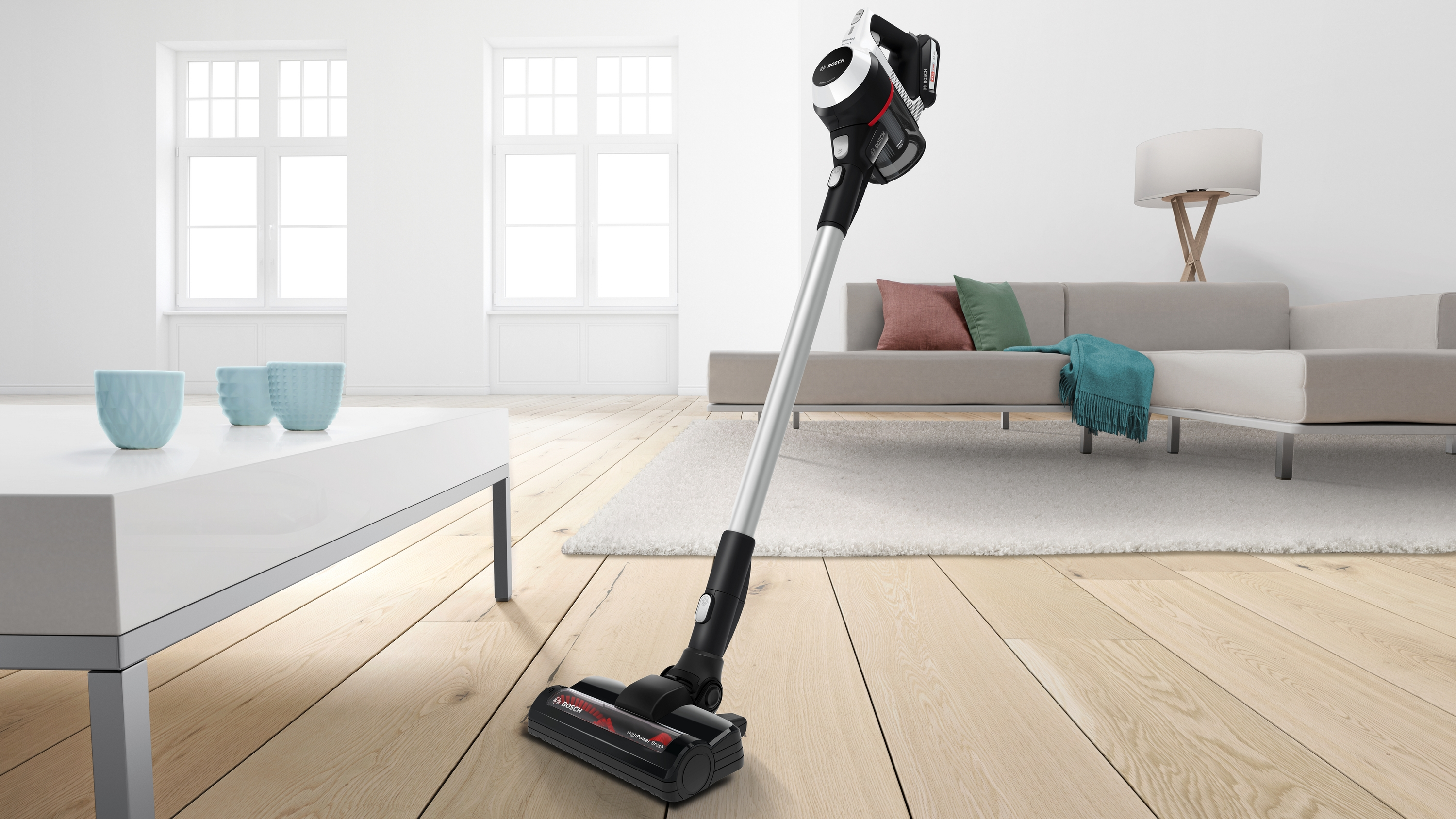 Ein kabelloser Staubsauger auf einem Holzboden, weiße Wände und Möbel im Hintergrund.