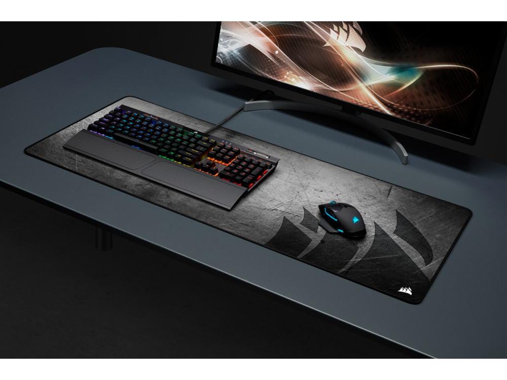 Una configuración de computadora: un teclado, un ratón y una alfombrilla sobre un escritorio gris oscuro.
