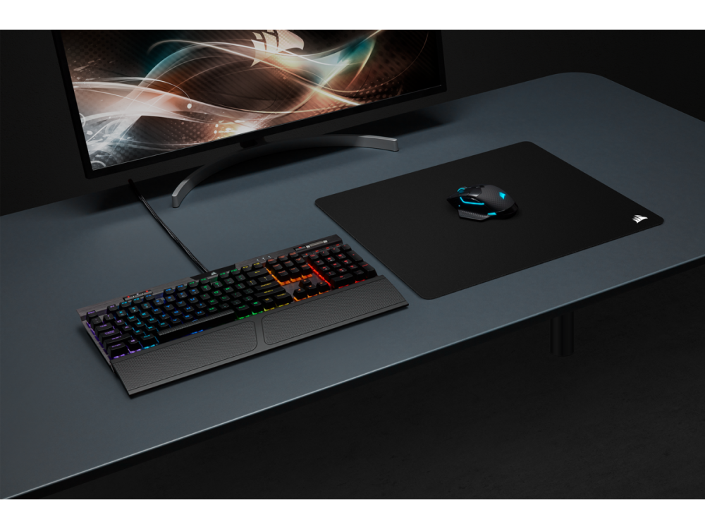 Una configuración de escritorio con teclado, ratón y monitor. Todo es de color oscuro, con el logo de Corsair.