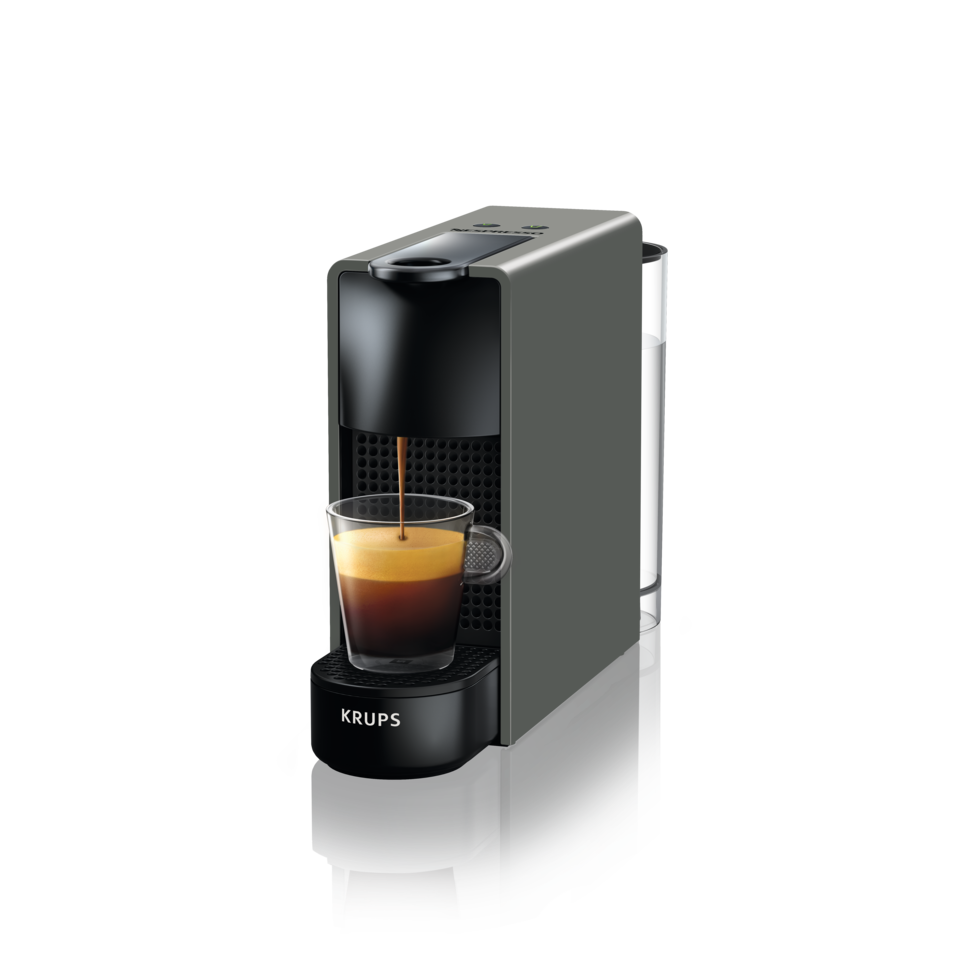 Kaffeemaschine, die Espresso in eine Glastasse ausgibt, schwarzer Oberflächenhintergrund.