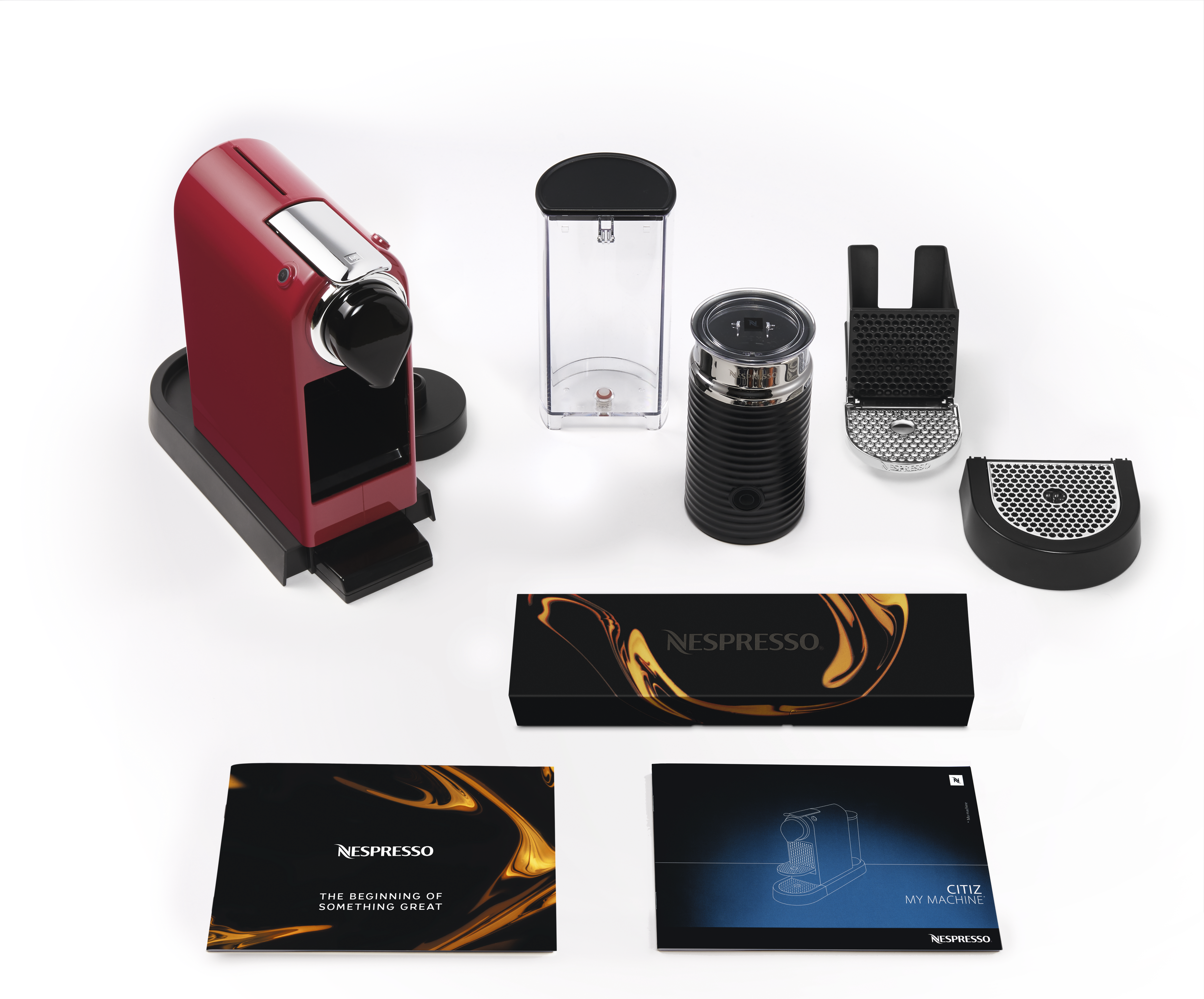 Rote Nespresso-Kaffeemaschine mit Zubehör auf weißer Oberfläche.