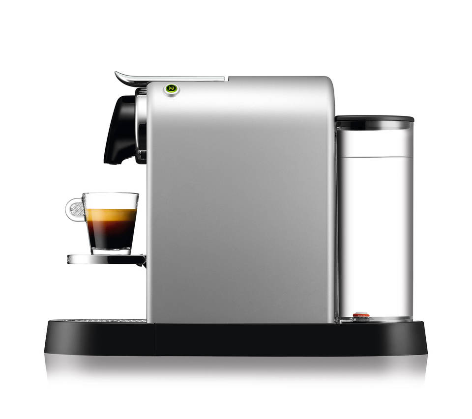Silberne Espressomaschine mit einer Tasse Kaffee auf einem Ständer. Schwarzer Sockel und Wassertank rechts.