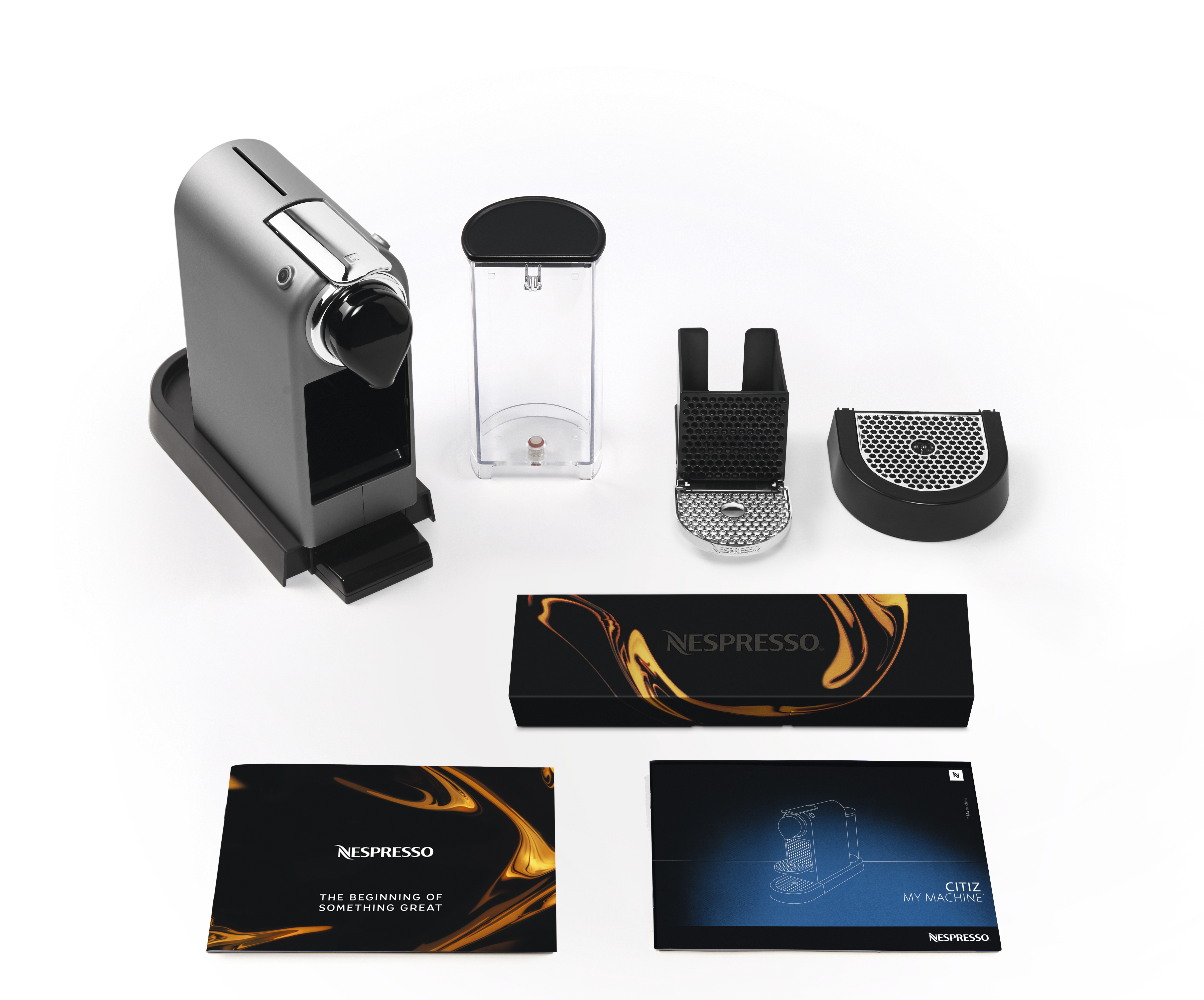 Eine silberne Nespresso-Kaffeemaschine mit Zubehör und Karton.