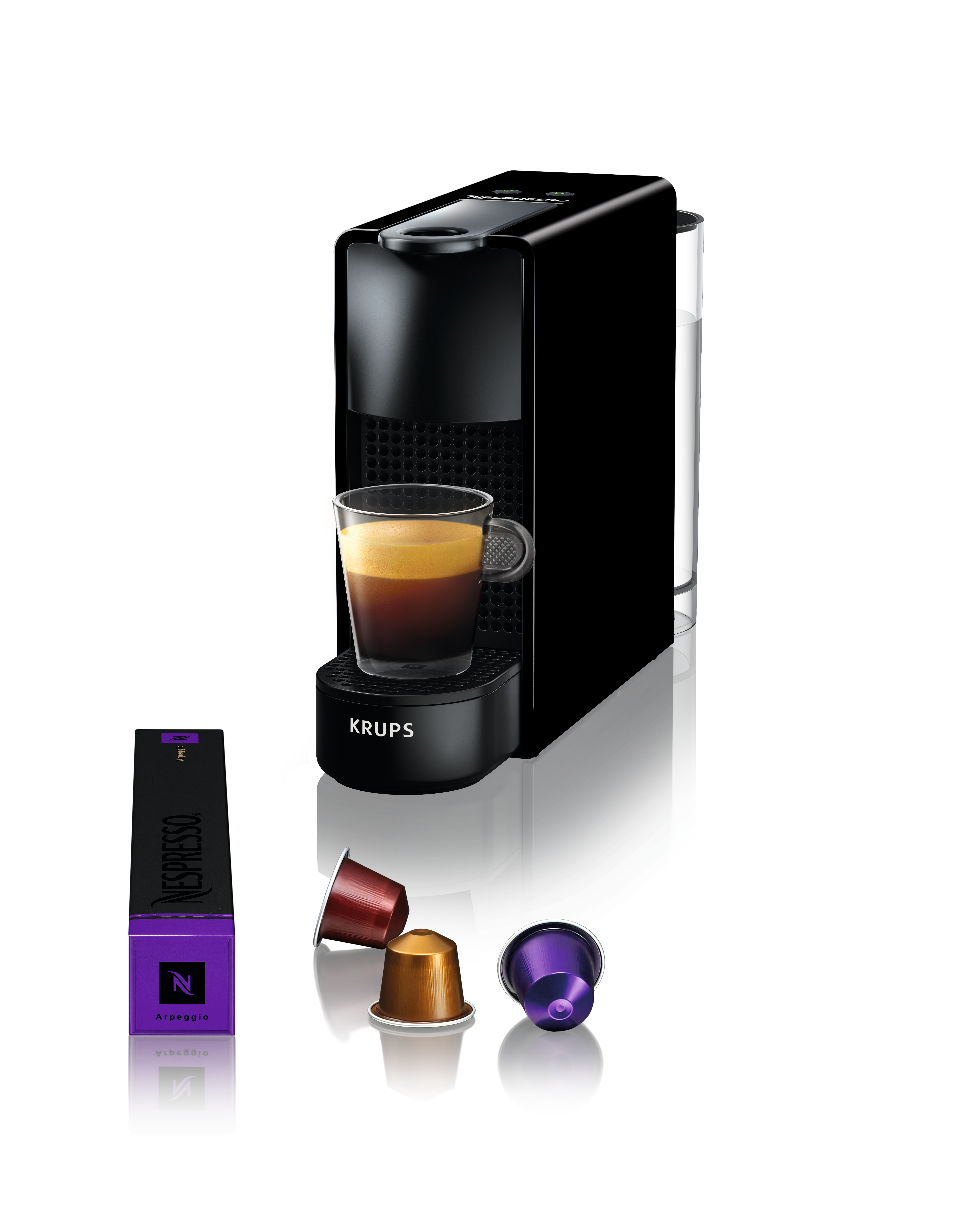 Eine schwarze Nespresso-Kaffeemaschine mit einem Glas Kaffee. In der Nähe befinden sich Kaffeekapseln und eine Nespresso-Box.