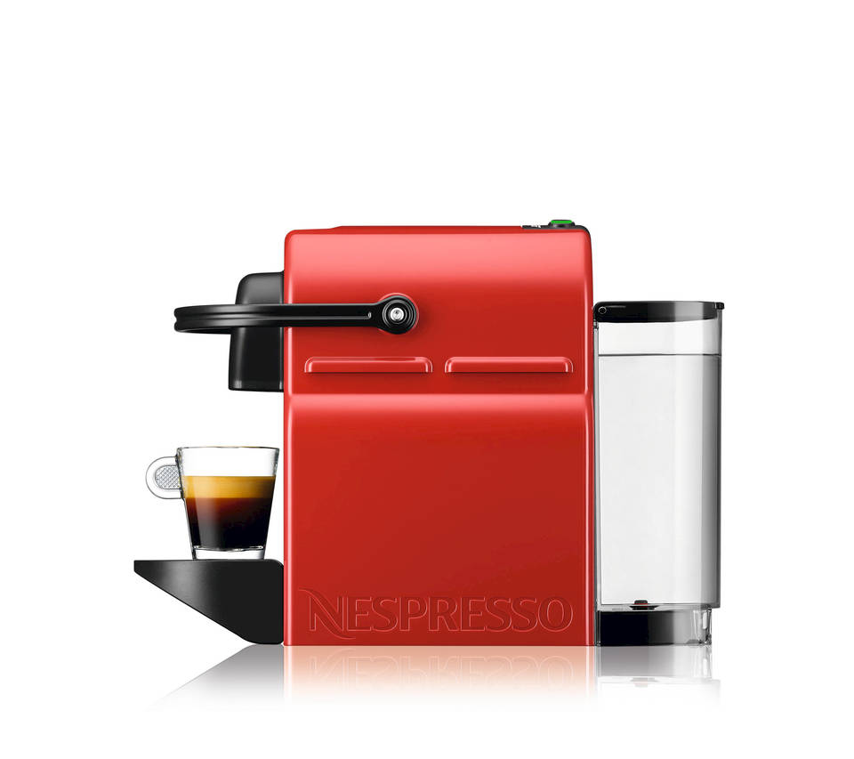 Rote Nespresso-Maschine mit Kaffeetasse und klarem Wasserbehälter, vor weißem Hintergrund.