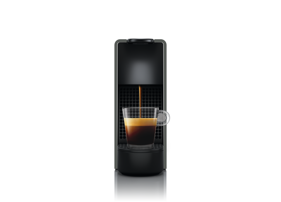 Eine schwarze Nespresso-Kaffeemaschine, die Kaffee in eine Glastasse gießt.