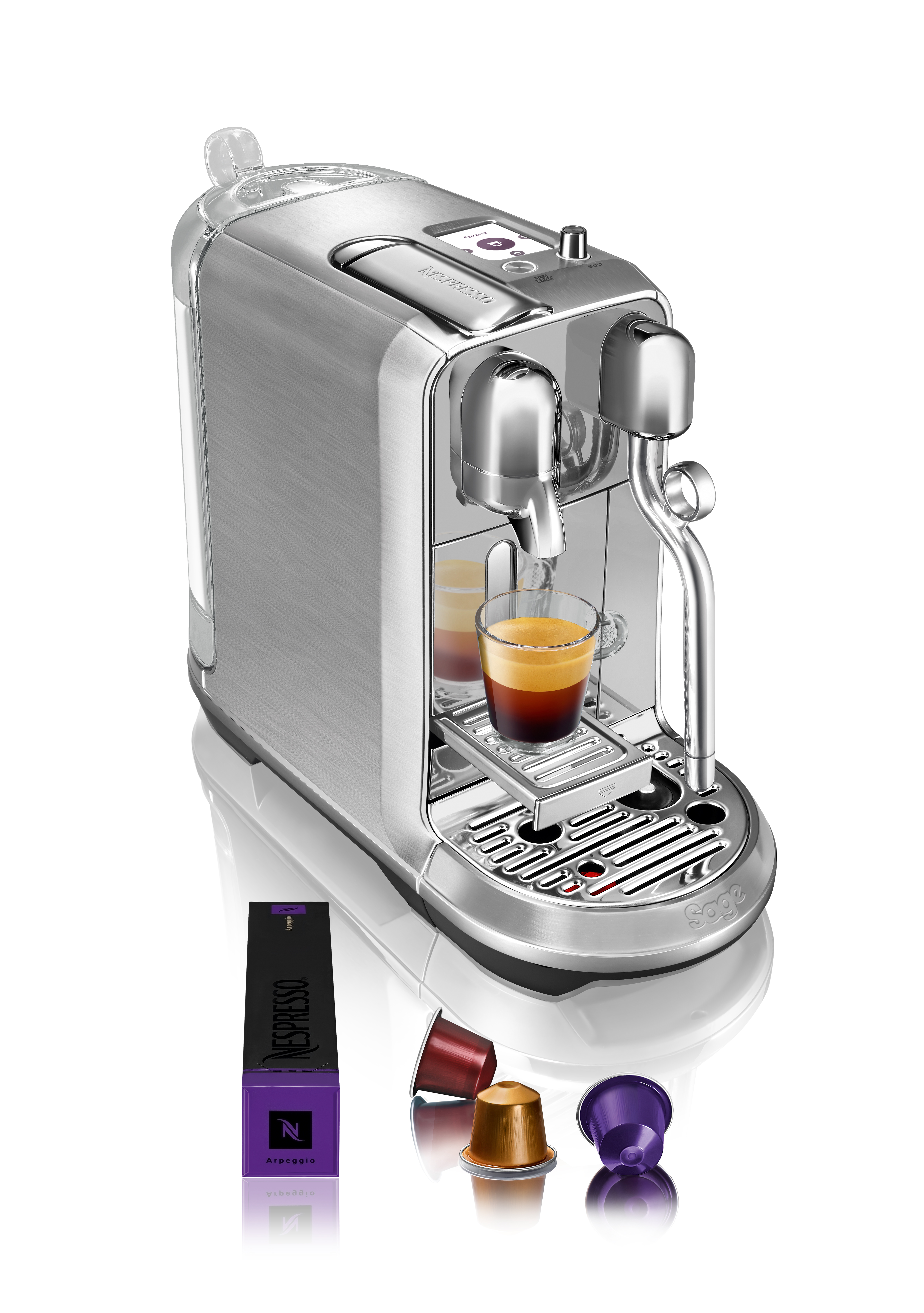 Eine silberne Espressomaschine mit einem Glas Espresso und Kaffeekapseln auf weißem Untergrund.