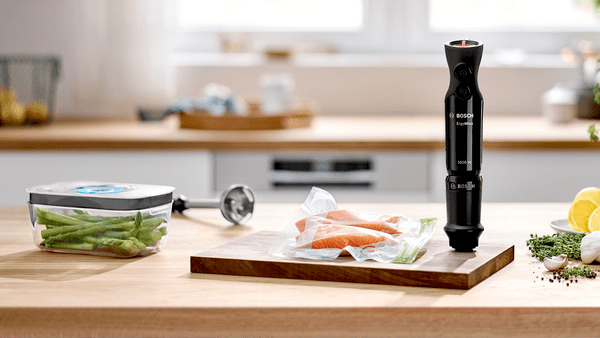 Eine Küchenszene mit einem Mixer, Lachs und Gemüse.