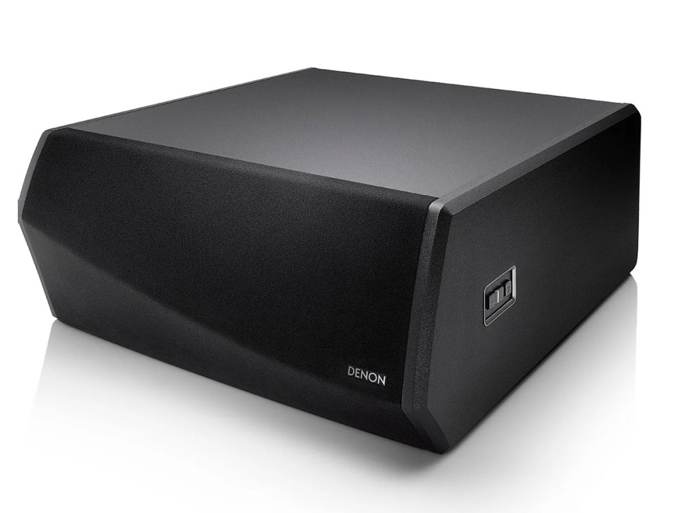 Subwoofer negro con un diseño curvo. Tiene el logotipo de Denon y está sobre una superficie blanca.